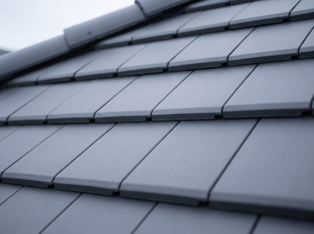 Close-up of clean anthracite grey concrete roof tiles.